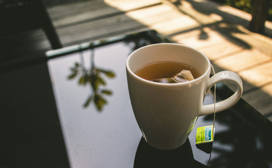 A quiet bedside scene with a steaming mug of herbal tea, soft lamp light, someone winding down for the night.