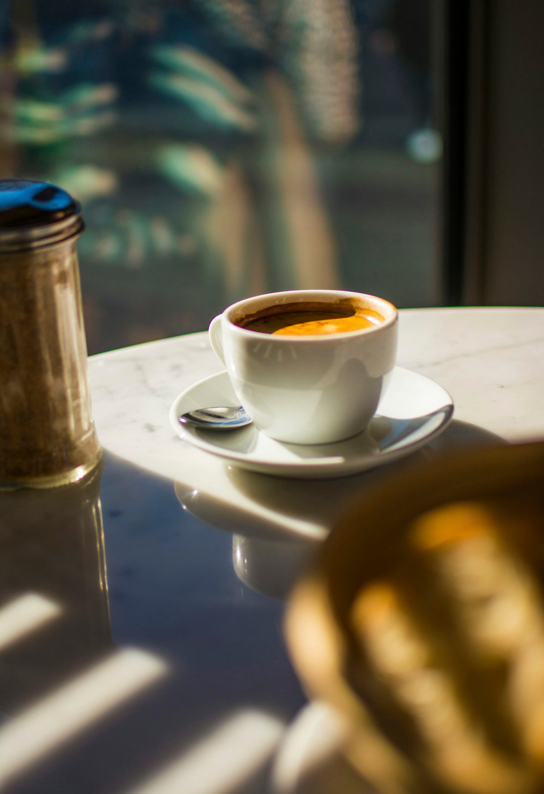 A calm morning coffee scene, someone sipping from a mug at a sunlit table, relaxed unhurried mood.