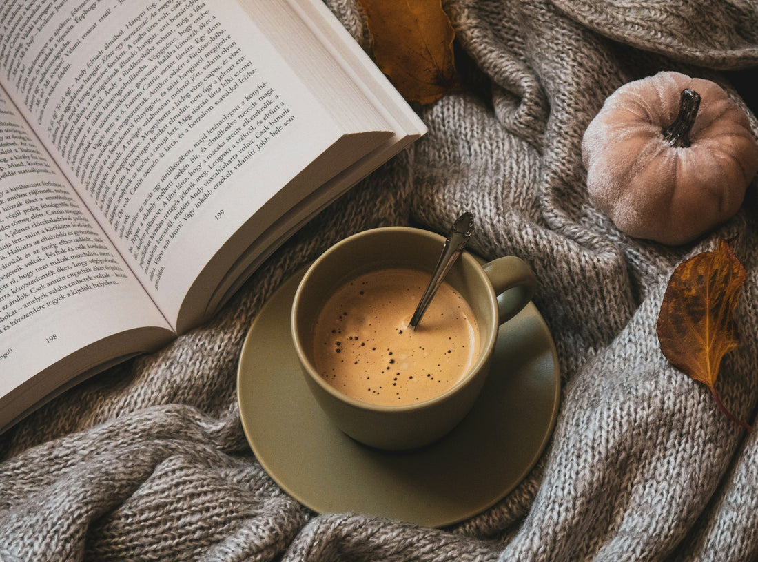 Cozy coffee corner with a knit blanket, book, and mini pumpkin