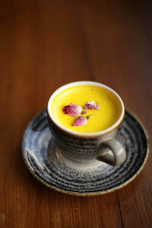 Golden milk turmeric latte with rose petals in a ceramic cup